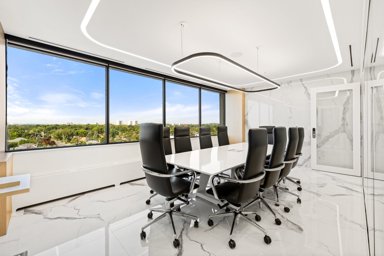 Modern conference room with a large table and chairs, large windows, and a cityscape view.