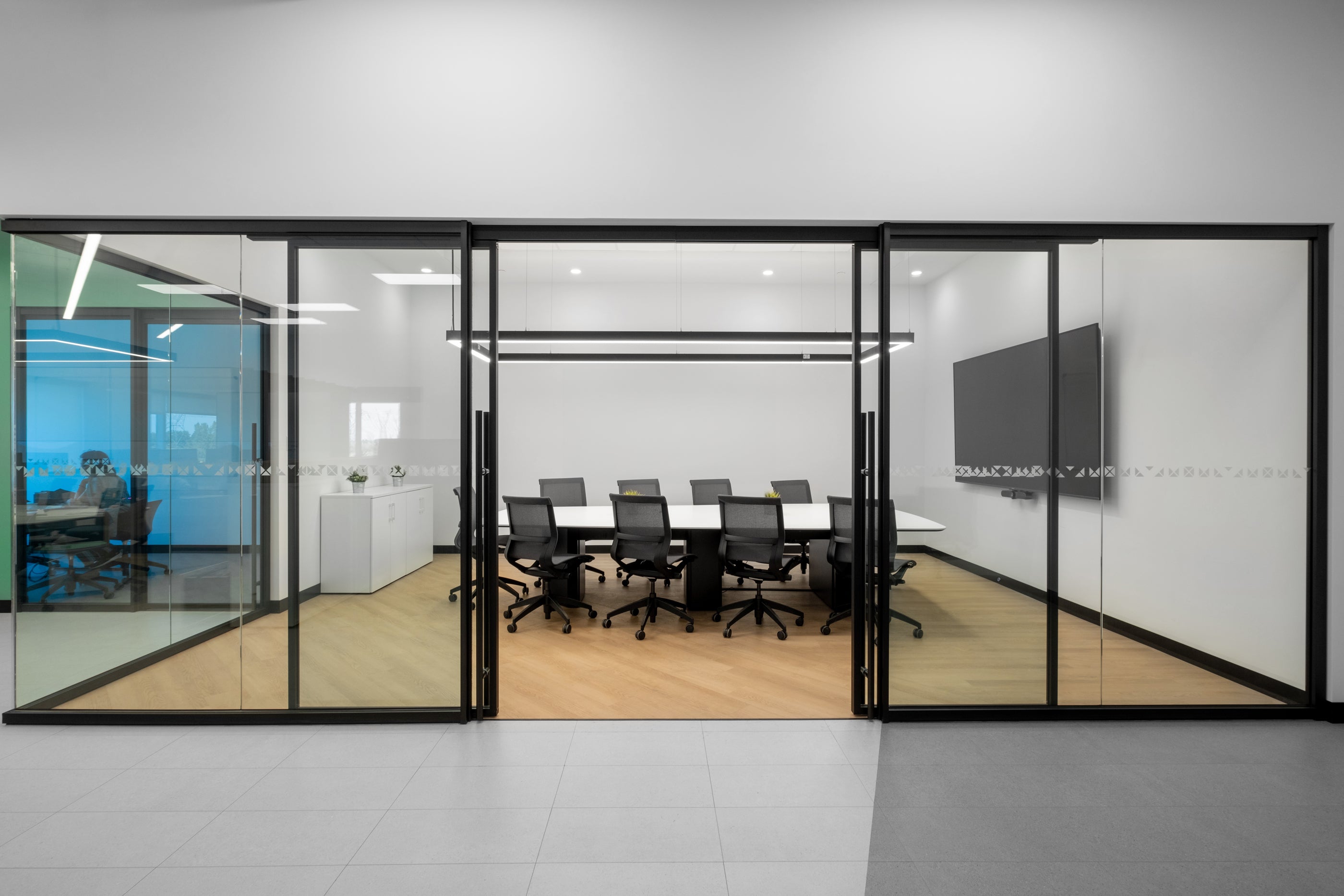 Modern office conference room with glass walls and a meeting table.