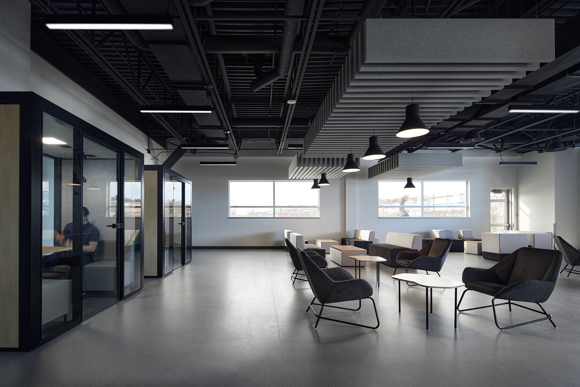 Modern office space with glass walls, tables, and chairs.