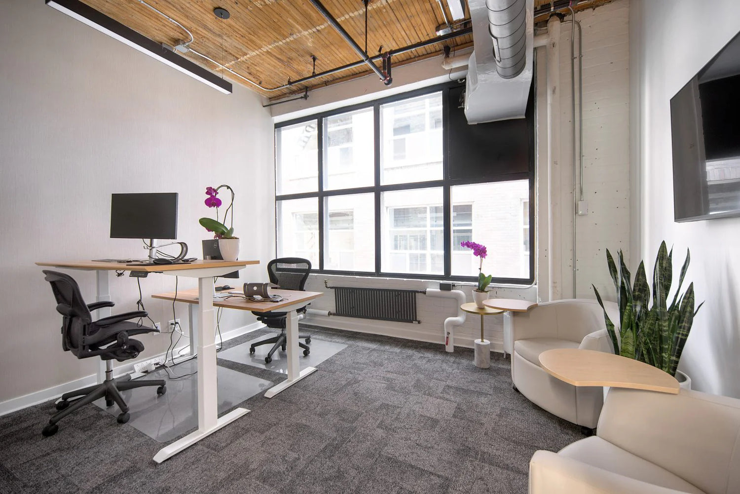 Modern office space with a desk, chairs, and large windows.