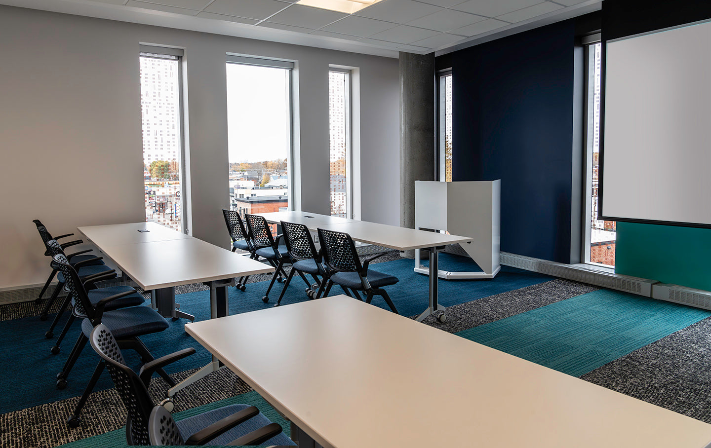 Modern conference room with tables, chairs, and a large screen.