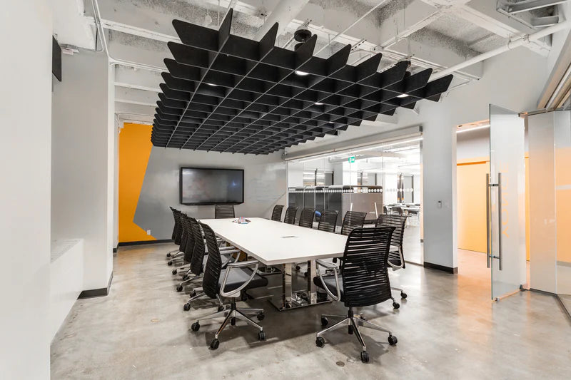 Modern conference room with a large table and chairs, featuring a TV on the wall.