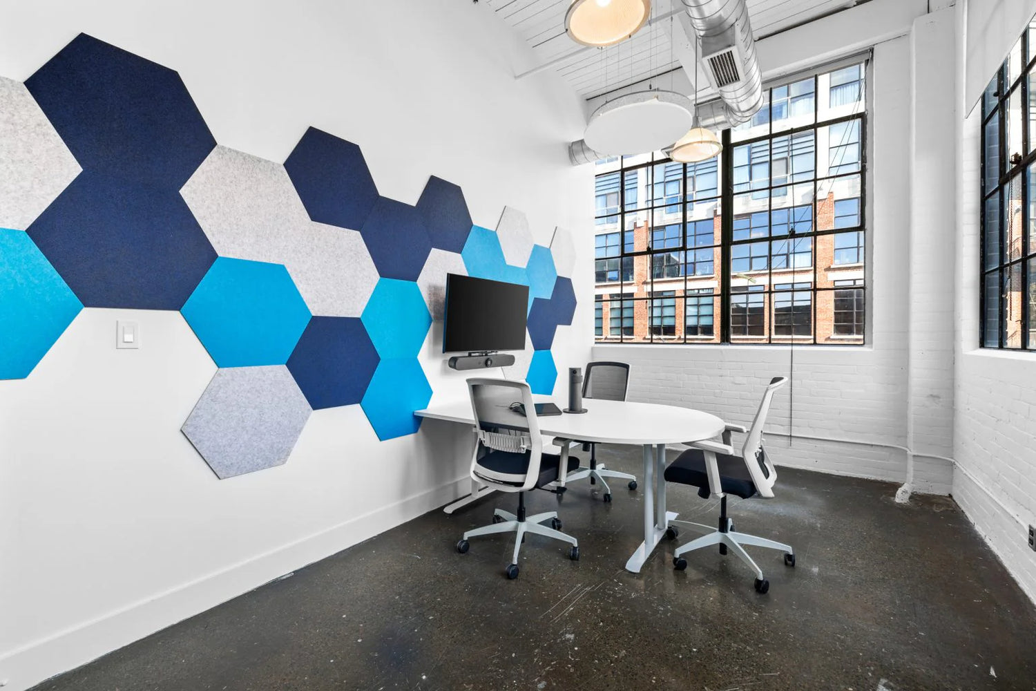 Modern office space with hexagonal blue and gray wall art, a white table, and chairs.