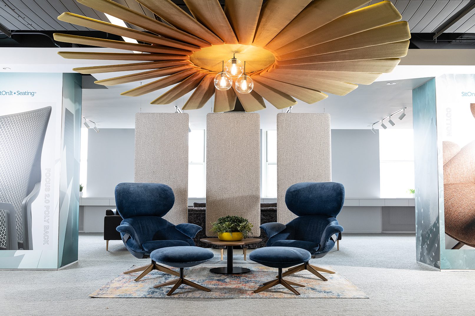 Modern office interior with blue chairs, round table, and decorative ceiling light fixture.