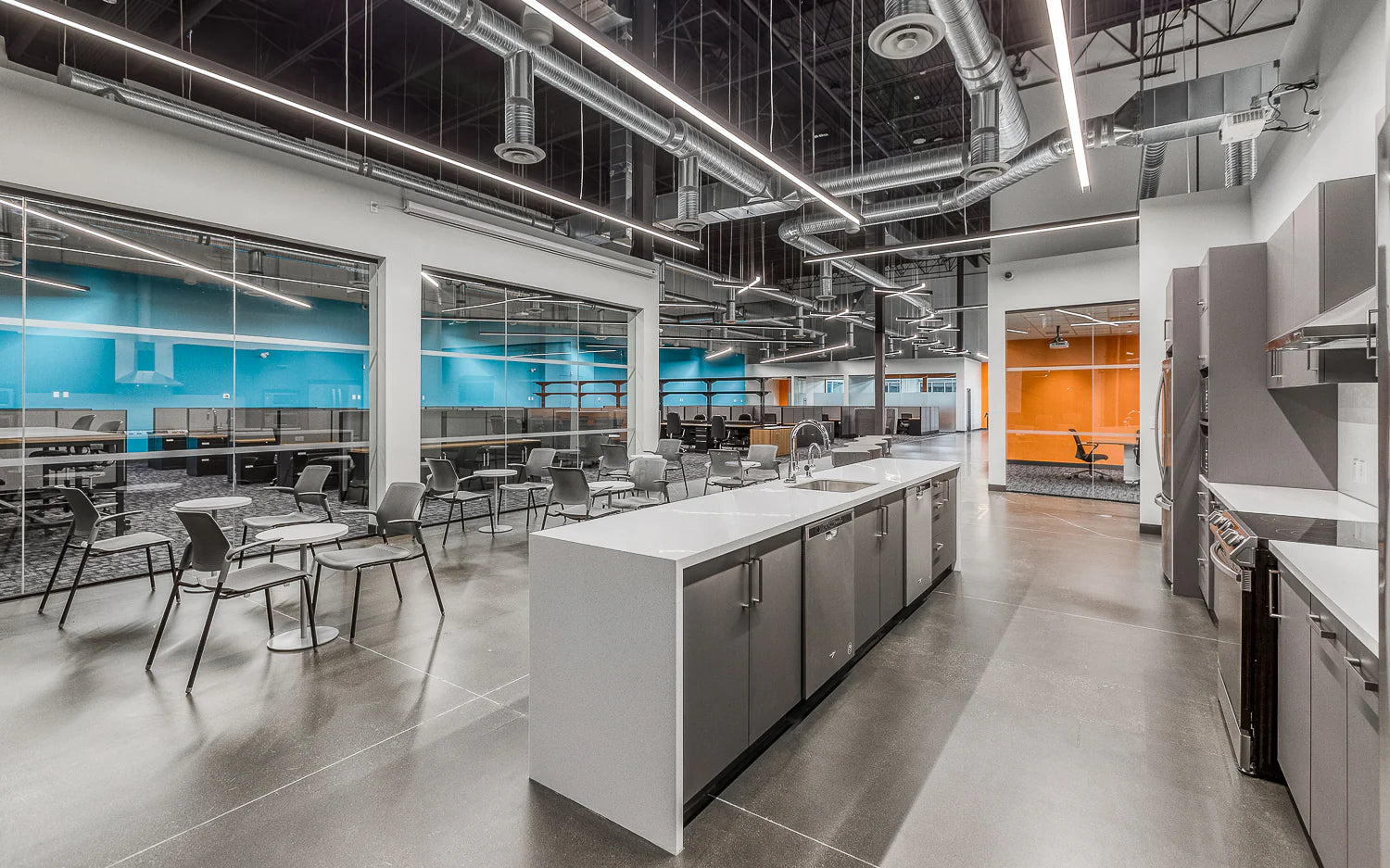 Modern office kitchen with island, chairs, and large windows