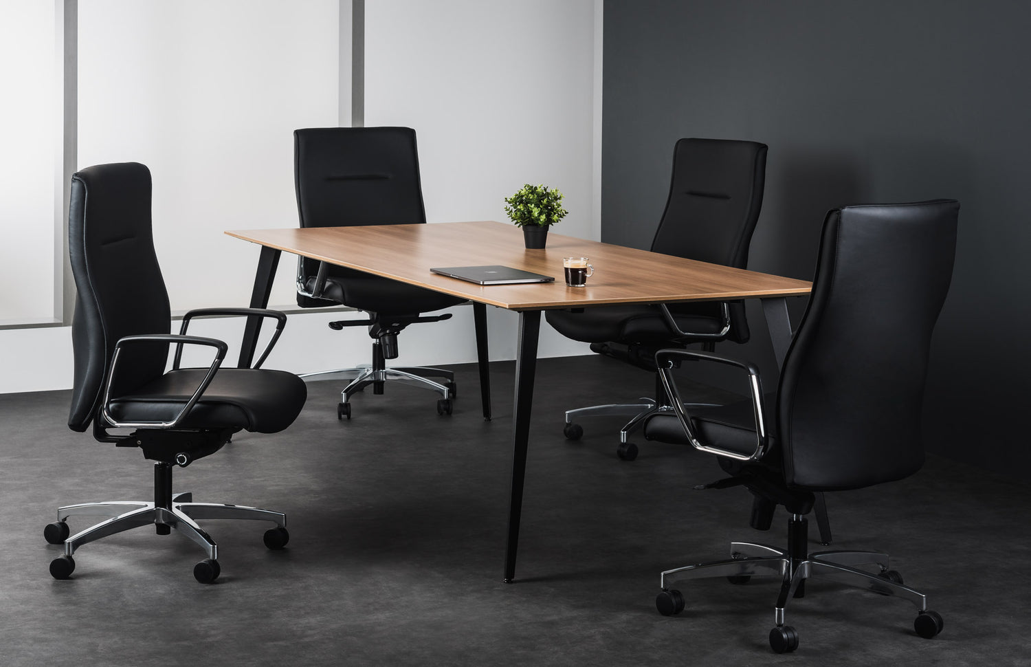 Modern office setup with a wooden desk and black office chairs in a minimalistic room.